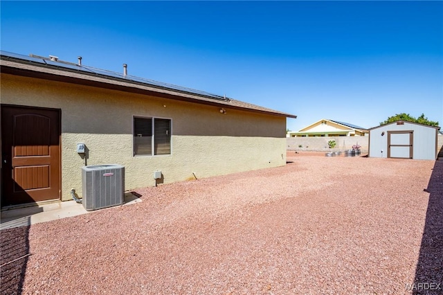 view of yard with fence, a storage shed, central AC unit, and an outbuilding
