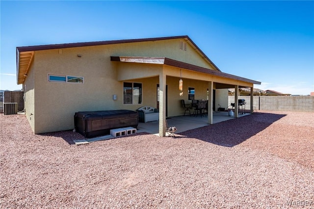 back of property with stucco siding, fence private yard, a hot tub, a patio, and cooling unit