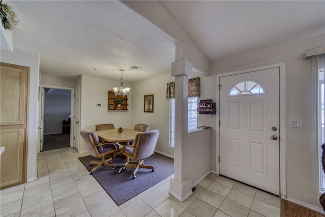 3408 Sunriver Rd Unit 207 B6, Bullhead City, AZ 86429 - entrance foyer with a chandelier, decorative columns, light tile patterned floors, baseboards, and a textured ceiling