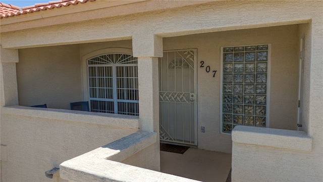 3408 Sunriver Rd Unit 207 B6, Bullhead City, AZ 86429 - doorway to property featuring stucco siding, a tiled roof, and covered porch