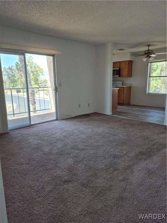 unfurnished living room featuring a textured ceiling, a ceiling fan, and light carpet