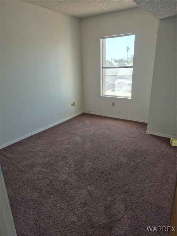 carpeted empty room with a textured ceiling and baseboards