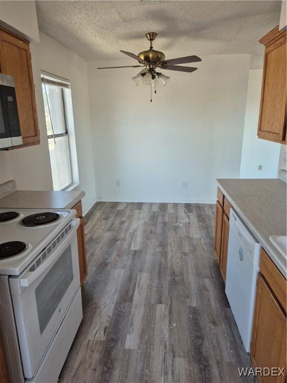 kitchen featuring dark wood-style floors, ceiling fan, brown cabinetry, white appliances, and a textured ceiling