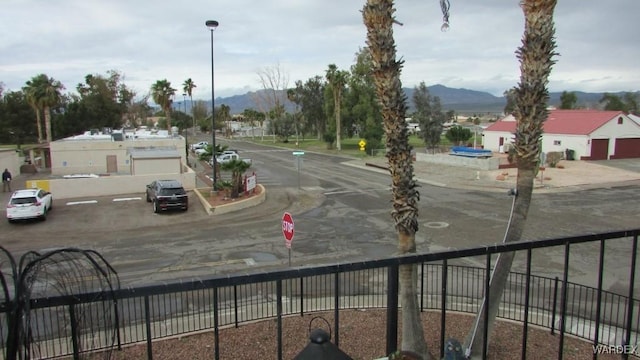 view of street featuring traffic signs, curbs, sidewalks, a mountain view, and street lights