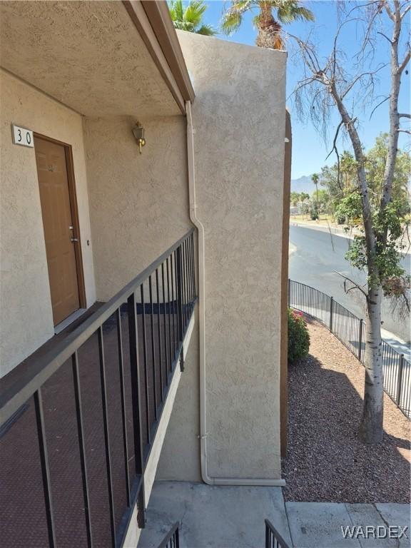 doorway to property with fence and stucco siding