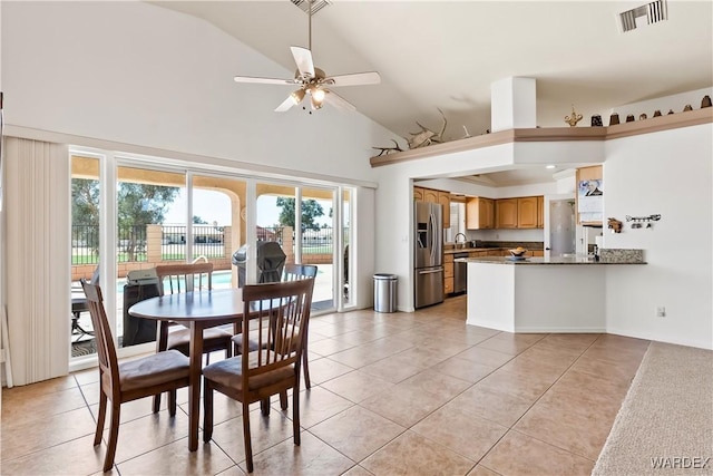 dining area featuring ceiling fan, high vaulted ceiling, light tile patterned floors, and visible vents