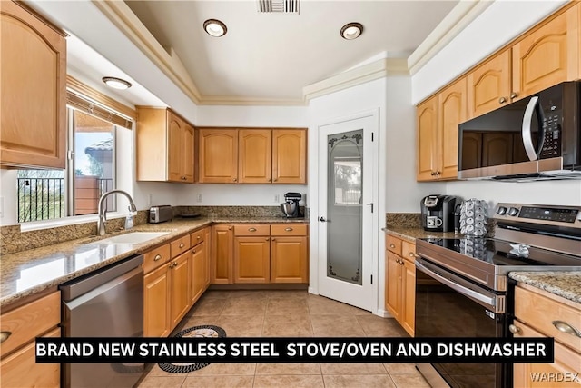 kitchen featuring light stone counters, appliances with stainless steel finishes, ornamental molding, light tile patterned flooring, and a sink