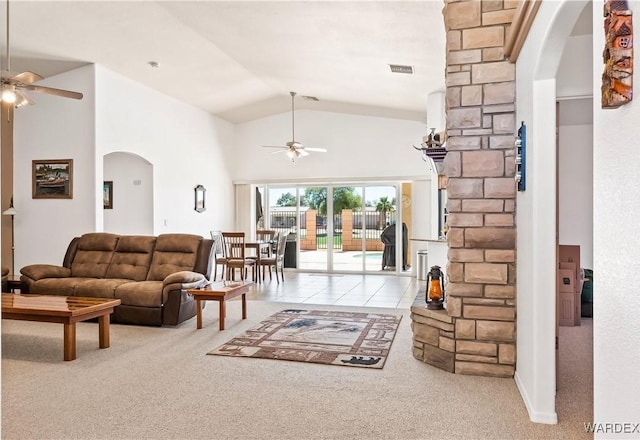 carpeted living area featuring arched walkways, high vaulted ceiling, visible vents, a ceiling fan, and tile patterned floors