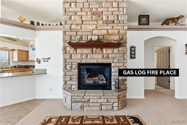 tiled living area featuring carpet, a sink, and a stone fireplace