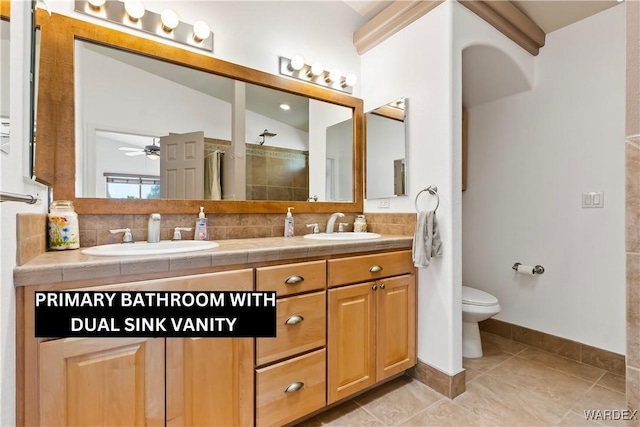 full bathroom with toilet, tasteful backsplash, double vanity, and a sink