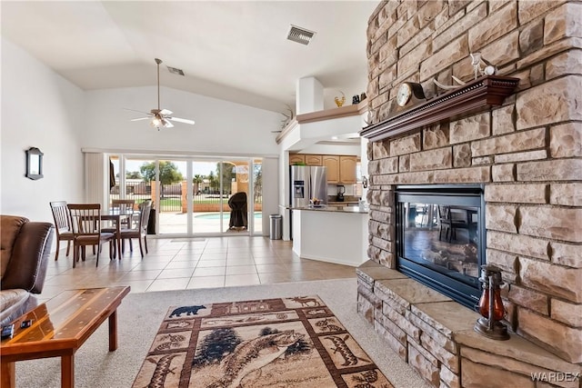 living room featuring light tile patterned floors, a fireplace, visible vents, and high vaulted ceiling