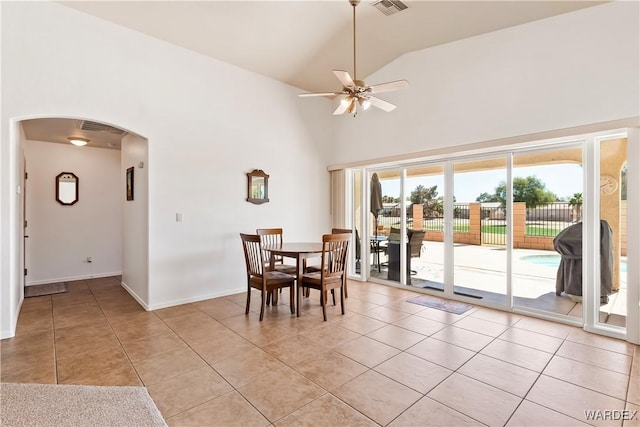 dining area with high vaulted ceiling, arched walkways, light tile patterned flooring, and ceiling fan