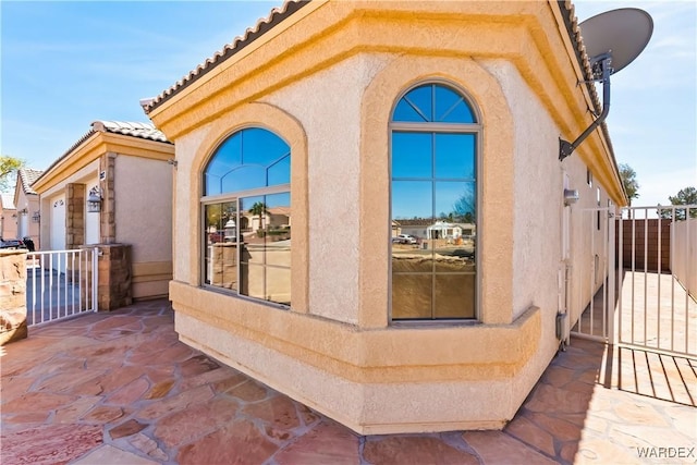 exterior space with a gate, fence, a tiled roof, and stucco siding