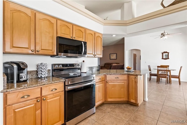 kitchen with arched walkways, electric range, dark stone counters, and light tile patterned flooring