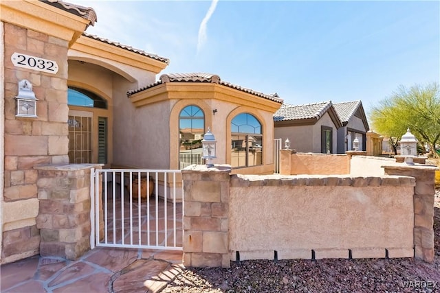 exterior space with a gate, a tile roof, and fence