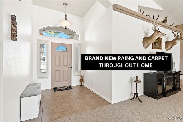 entrance foyer with visible vents, a high ceiling, carpet flooring, tile patterned flooring, and baseboards