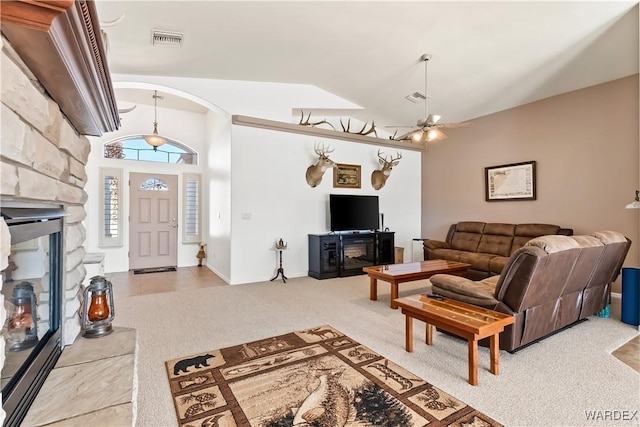 living area featuring carpet floors, ceiling fan, visible vents, and a stone fireplace