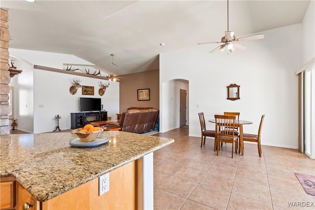 kitchen featuring lofted ceiling, light tile patterned floors, arched walkways, and a ceiling fan