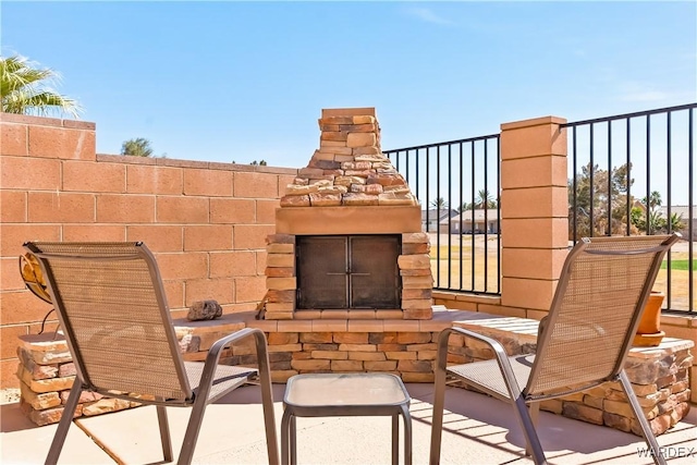 view of patio / terrace with fence and an outdoor stone fireplace