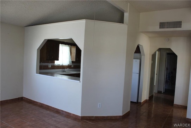 kitchen with a textured ceiling, tile patterned flooring, visible vents, and baseboards