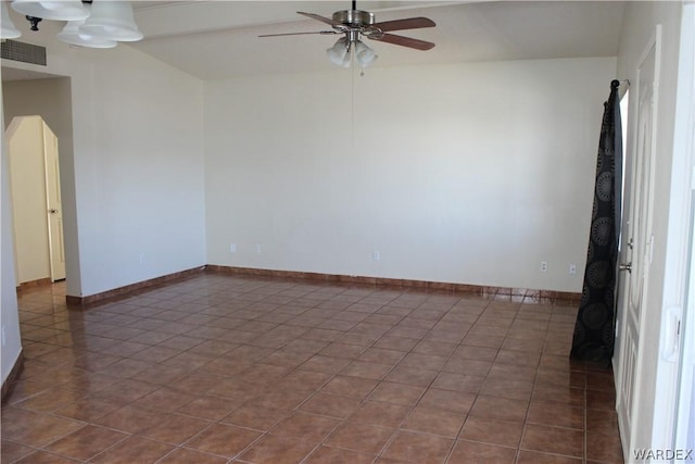 spare room featuring baseboards, visible vents, a ceiling fan, and dark tile patterned flooring