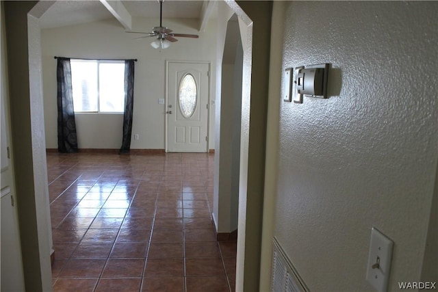 entrance foyer with visible vents, arched walkways, a ceiling fan, beamed ceiling, and dark tile patterned floors