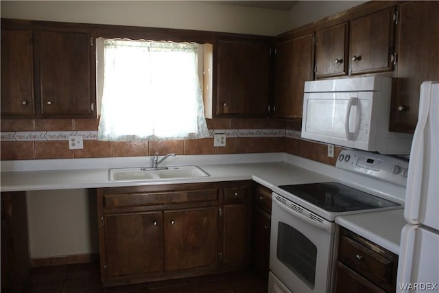 kitchen featuring light countertops, decorative backsplash, a sink, dark brown cabinetry, and white appliances