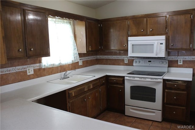 kitchen with white appliances, backsplash, light countertops, and a sink