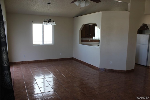 empty room with baseboards, arched walkways, a textured ceiling, dark tile patterned floors, and ceiling fan with notable chandelier