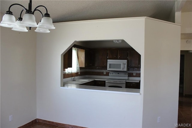 kitchen with dark brown cabinetry, white appliances, dark tile patterned floors, a sink, and decorative light fixtures