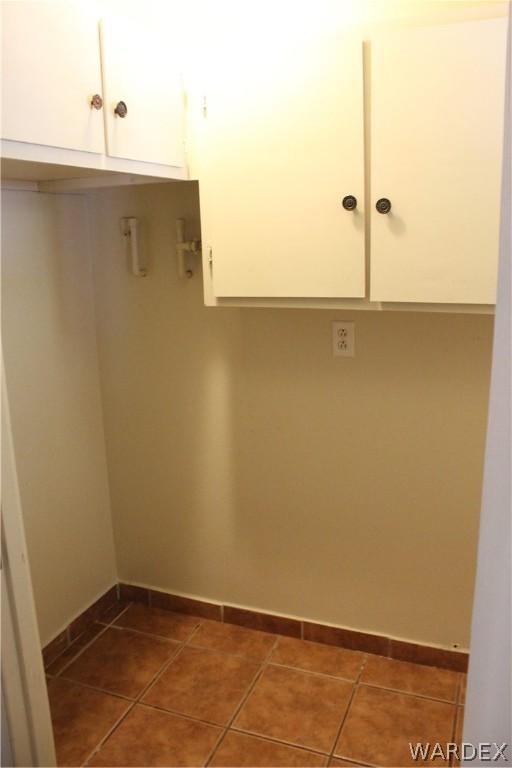 laundry area with dark tile patterned flooring and baseboards