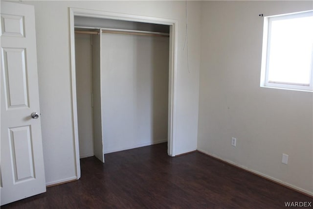 unfurnished bedroom with dark wood-style floors and a closet