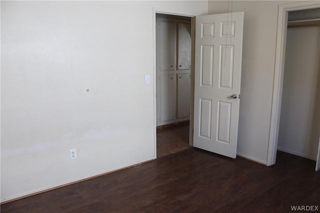 unfurnished bedroom with dark wood-style floors, a closet, and baseboards