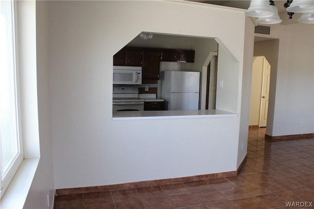 kitchen with light countertops, visible vents, dark brown cabinetry, tile patterned flooring, and white appliances