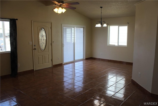 foyer featuring a textured ceiling, lofted ceiling, ceiling fan with notable chandelier, dark tile patterned floors, and baseboards