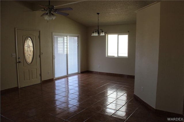 foyer featuring a textured ceiling, lofted ceiling, ceiling fan with notable chandelier, dark tile patterned floors, and baseboards