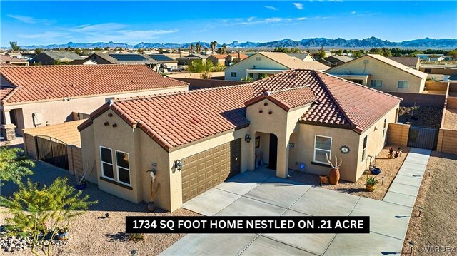 view of front of property with a mountain view, a tiled roof, concrete driveway, a residential view, and stucco siding