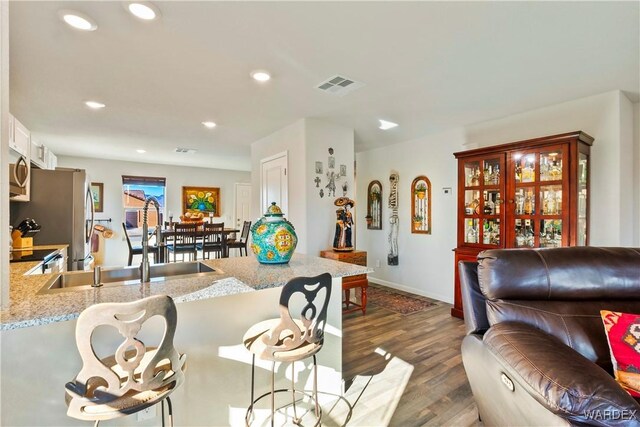 living area featuring dark wood-style floors, recessed lighting, visible vents, and baseboards