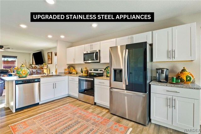 kitchen featuring recessed lighting, a peninsula, white cabinetry, appliances with stainless steel finishes, and light wood finished floors