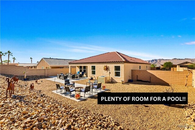 back of house with stucco siding, a fenced backyard, a mountain view, and a patio