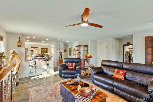 living area featuring recessed lighting, visible vents, a ceiling fan, wood finished floors, and baseboards