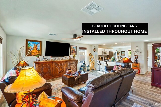 living room featuring light wood-style flooring, plenty of natural light, and visible vents