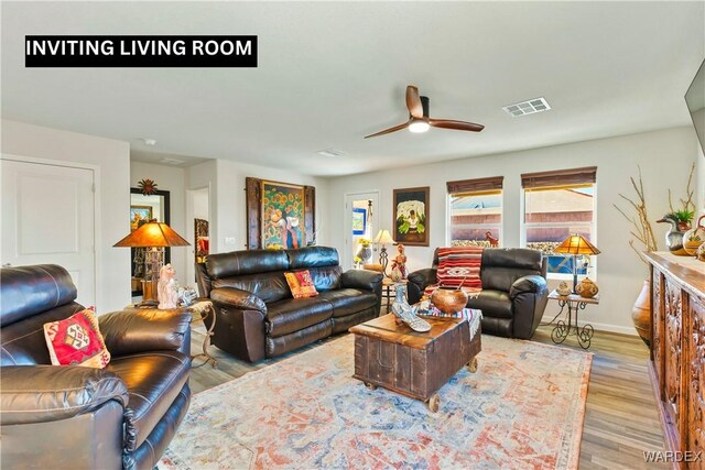 living area featuring a ceiling fan, baseboards, visible vents, and wood finished floors