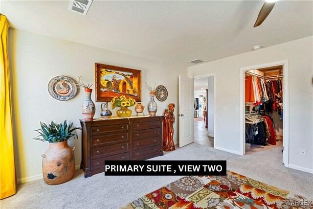 bedroom featuring light colored carpet, a walk in closet, visible vents, and a ceiling fan