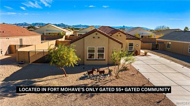 mediterranean / spanish house with a tile roof, fence, a mountain view, and stucco siding