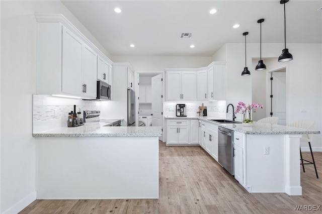 kitchen with pendant lighting, a peninsula, appliances with stainless steel finishes, and white cabinets