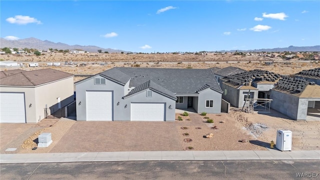 single story home with decorative driveway, an attached garage, a mountain view, and stucco siding