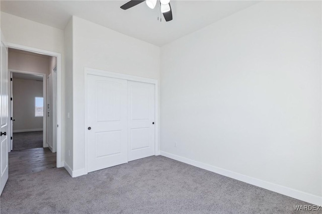 unfurnished bedroom with light carpet, a closet, a ceiling fan, and baseboards