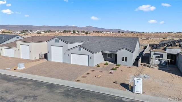 view of front of house with a garage, a residential view, decorative driveway, a mountain view, and stucco siding