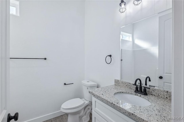 bathroom featuring a wealth of natural light, baseboards, vanity, and toilet